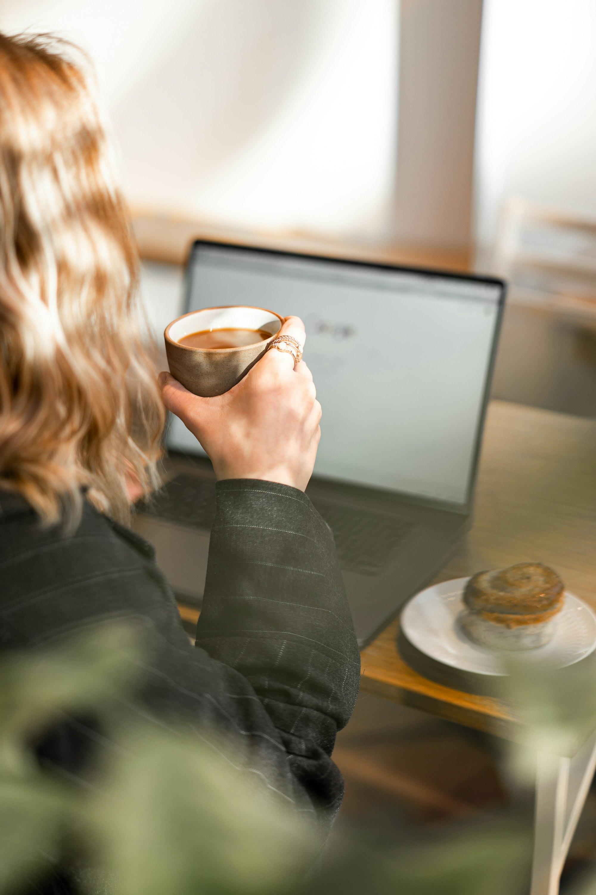 A person with a coffee working at a laptop