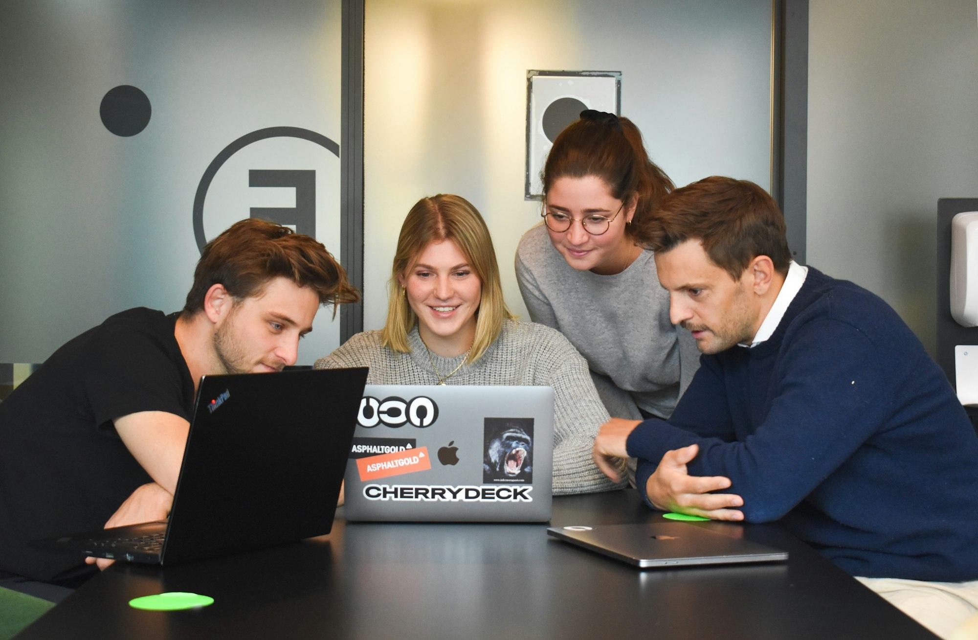 Four people reviewing a design together on a laptop