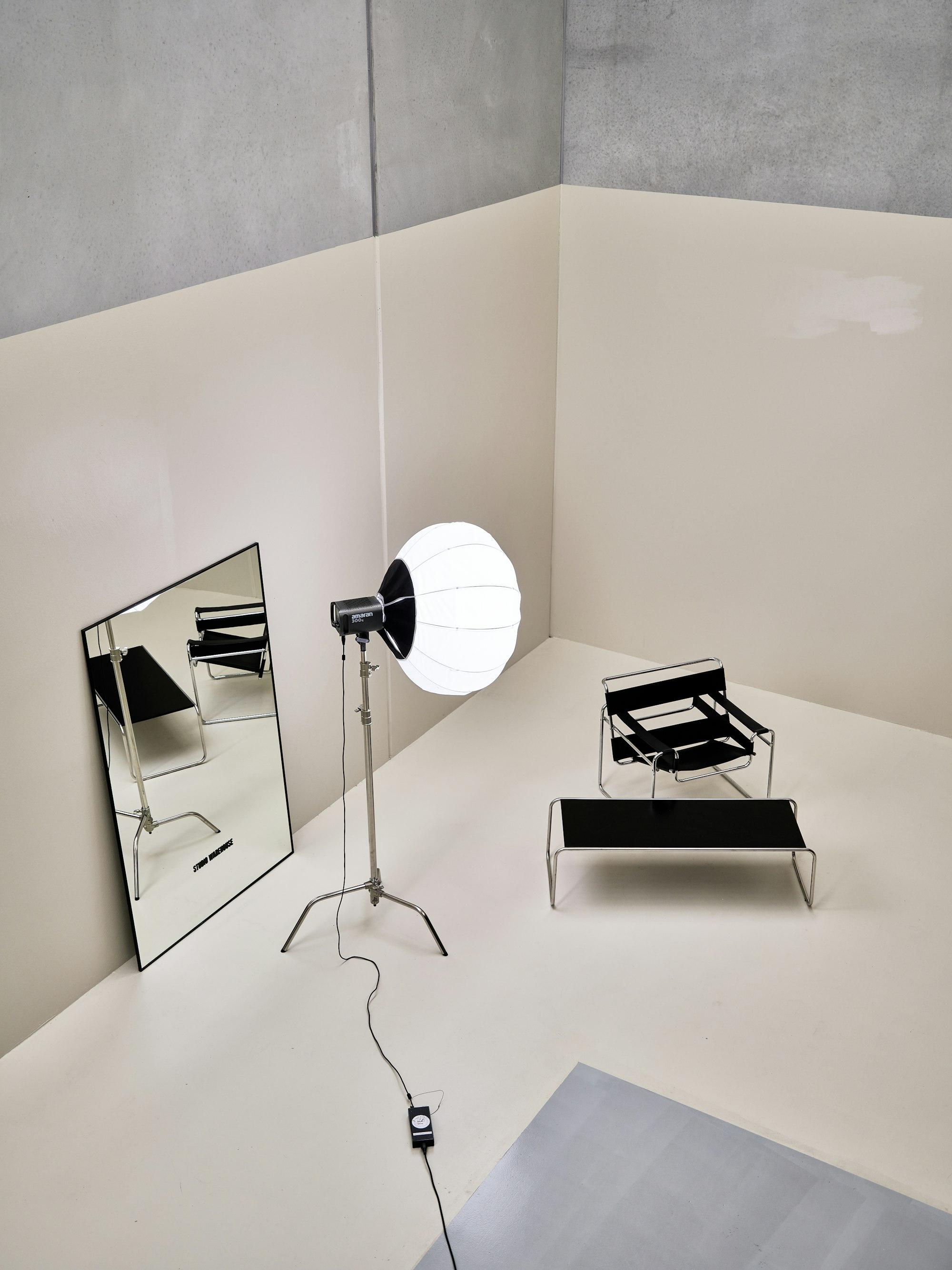 A white photo studio with a lantern light, a mirror and a chair